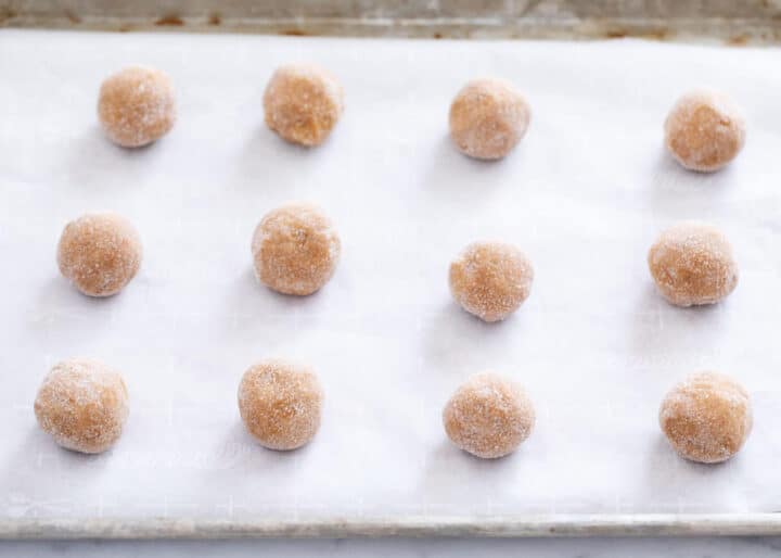 molasses cookie dough balls rolled in sugar on baking sheet 