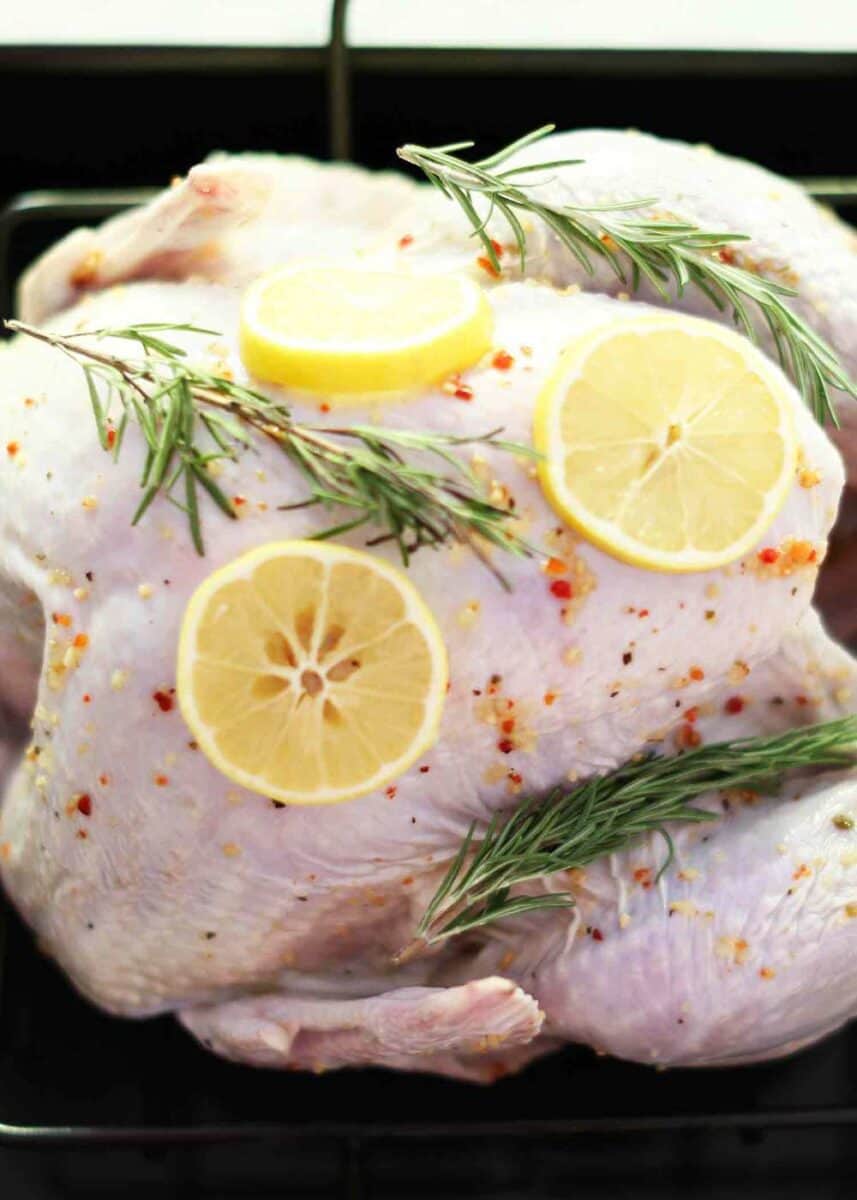 raw turkey covered with brine, rosemary and lemon slices 