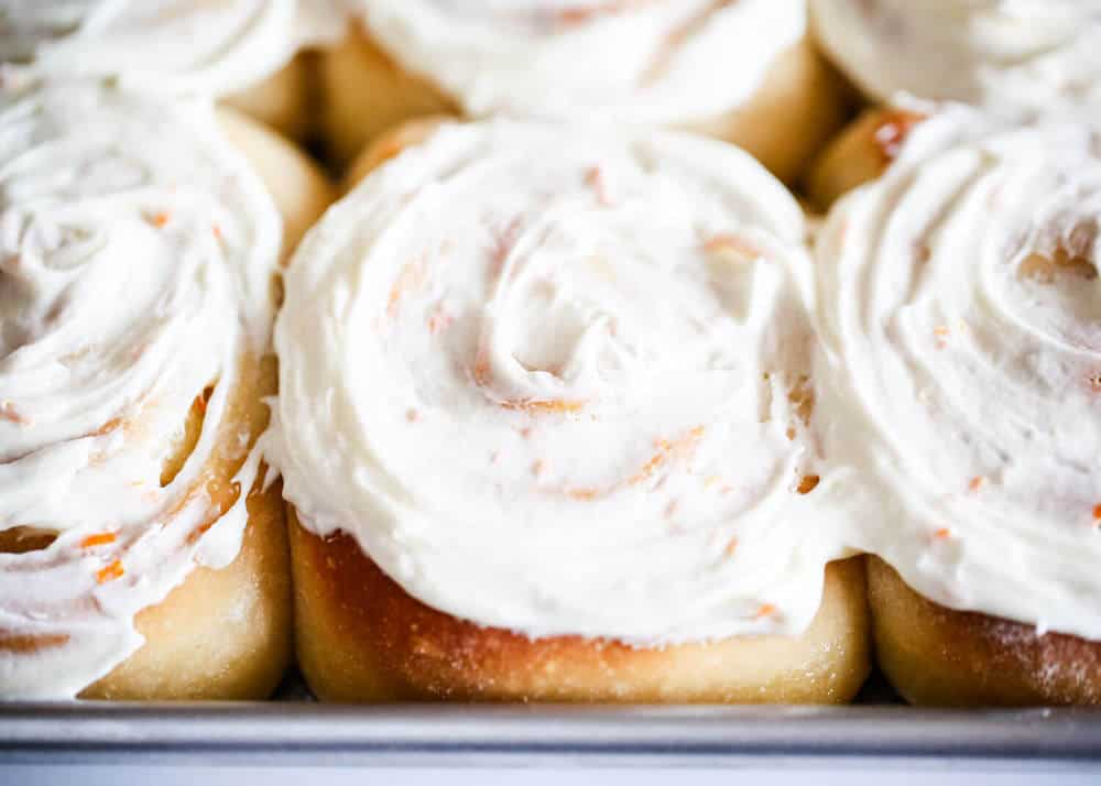 Frosted orange rolls in pan.