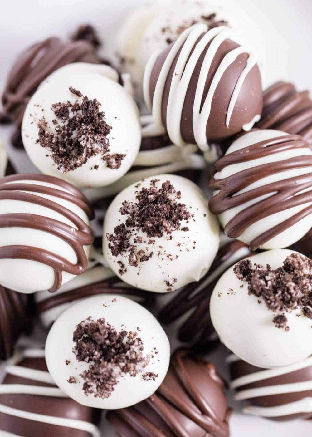 These OREO cookie balls are made with just 3 simple ingredients and are such an easy dessert recipe! They are fun, festive and great to make for entertaining. Drizzle with chocolate or top with your favorite colored sprinkles for the perfect decorative treat! oreo truffle balls stacked on top of a white plate