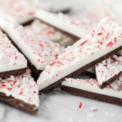 Stacked peppermint bark pieces with dark chocolate, white chocolate and crushed candy canes on top.
