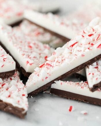 Stacked peppermint bark pieces with dark chocolate, white chocolate and crushed candy canes on top.