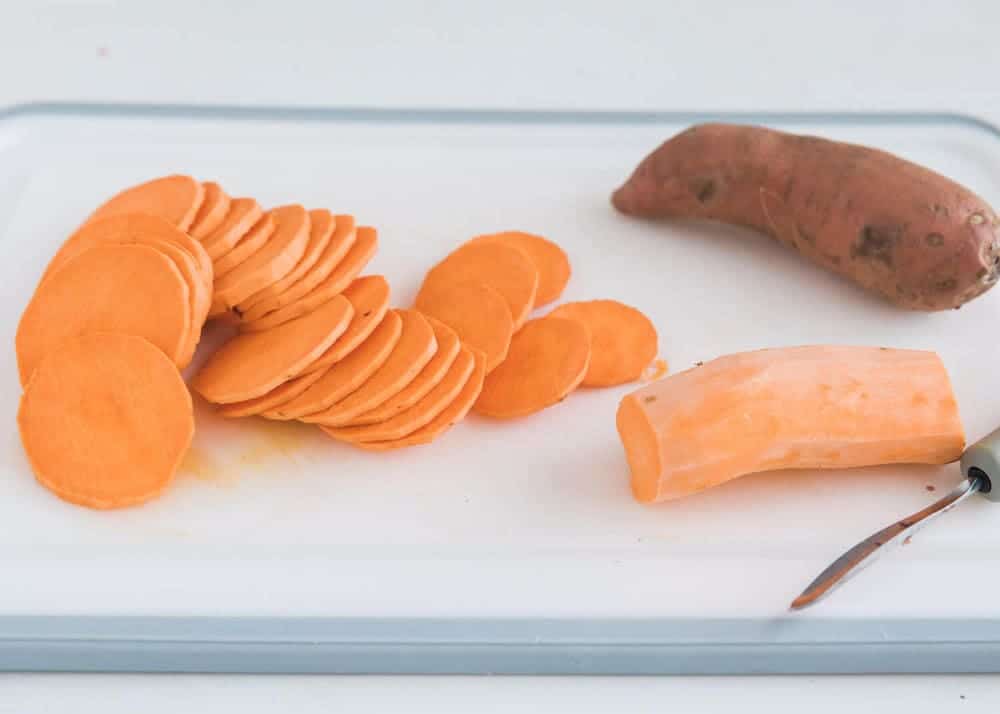 Slicing sweet potatoes on cutting board.