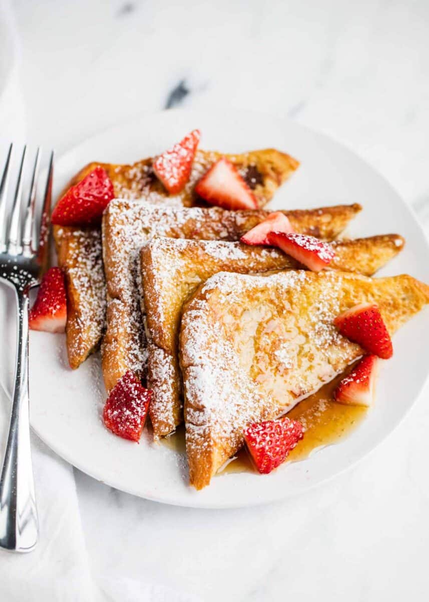 homemade french toast with strawberries, powdered sugar and syrup 