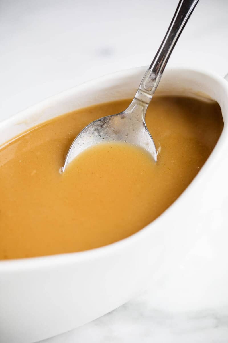 brown gravy in a white gravy boat with a spoon 