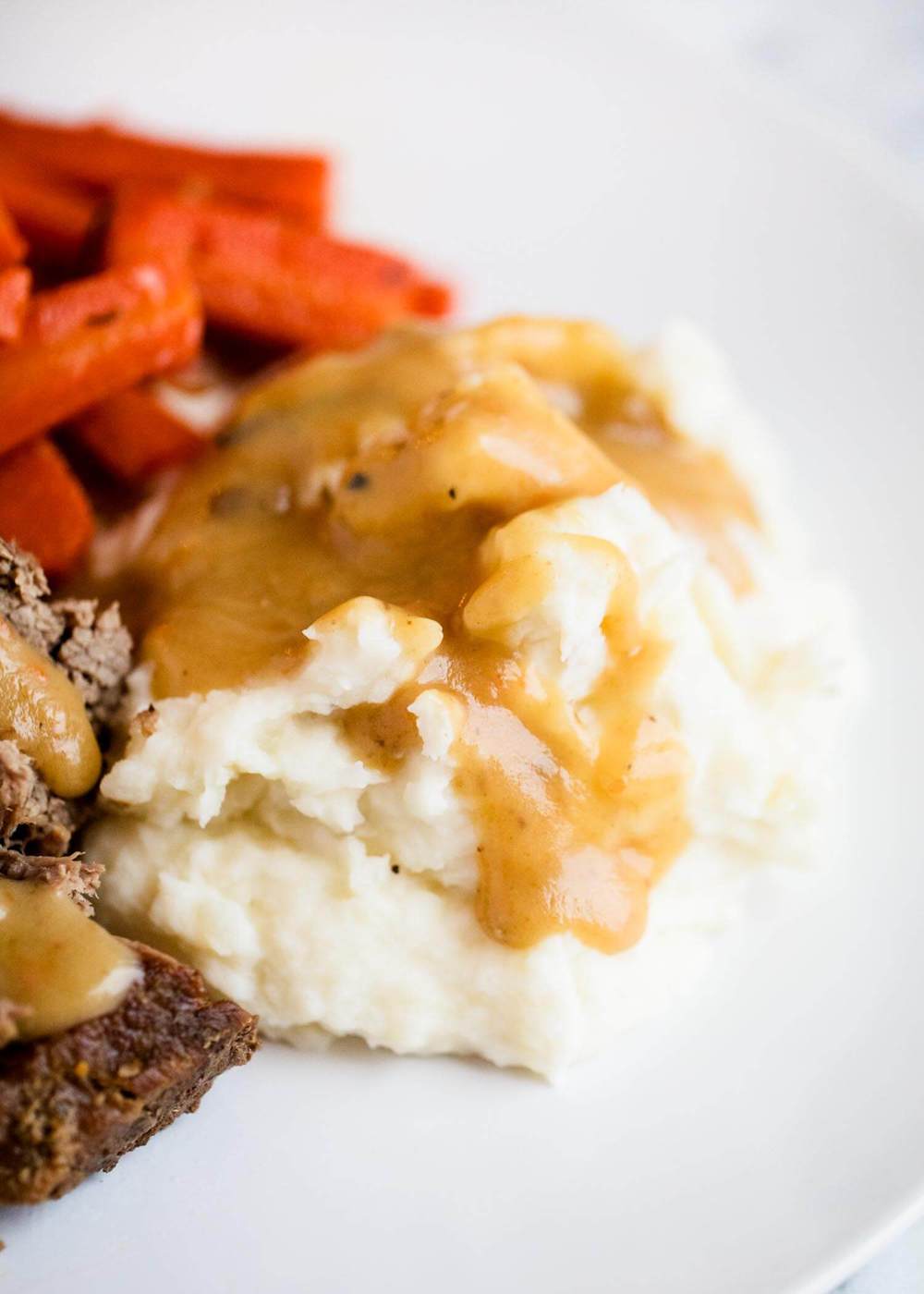 Pot roast, carrots and mashed potatoes with gravy on top.