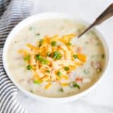 bowl of ham and potato soup topped with cheese and chives