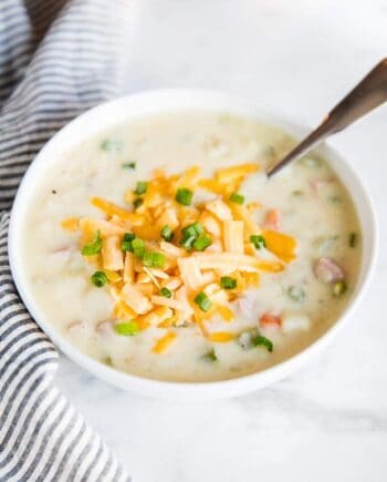 bowl of ham and potato soup topped with cheese and chives