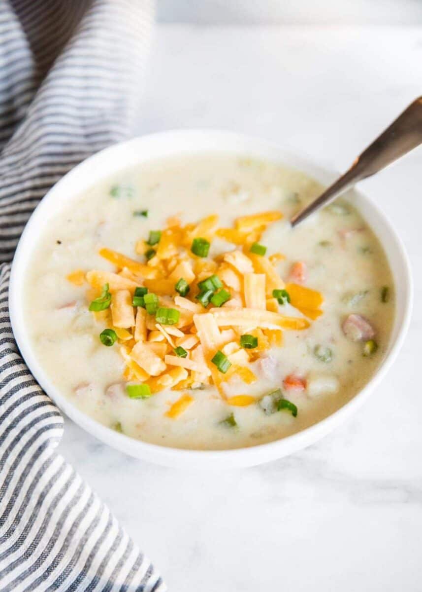 bowl of ham and potato soup topped with cheese and chives 