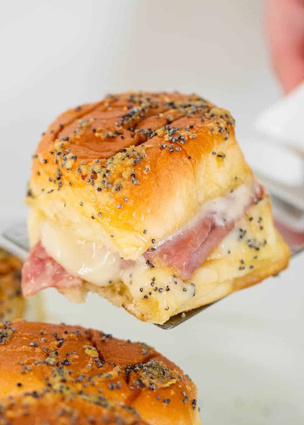 Lifting ham and cheese roll out of baking dish.