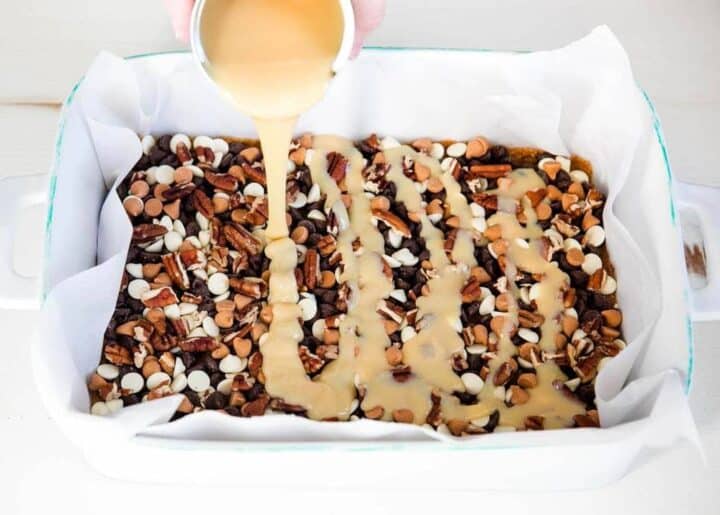 pouring condensed milk on top of seven layer bars