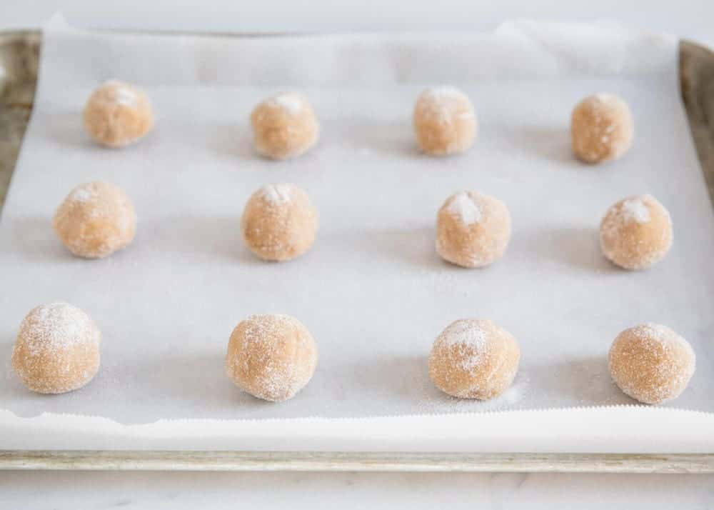 Peanut butter blossom cookie dough balls on baking sheet.