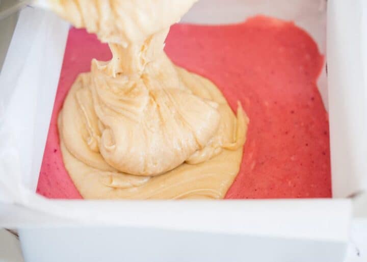 pouring peanut butter fudge on top of strawberry fudge 