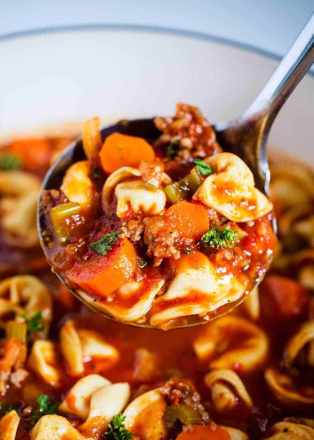 Sausage tortellini soup in ladle.