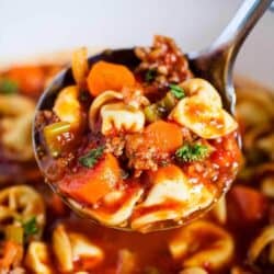 close up of sausage tortellini soup on a silver ladle