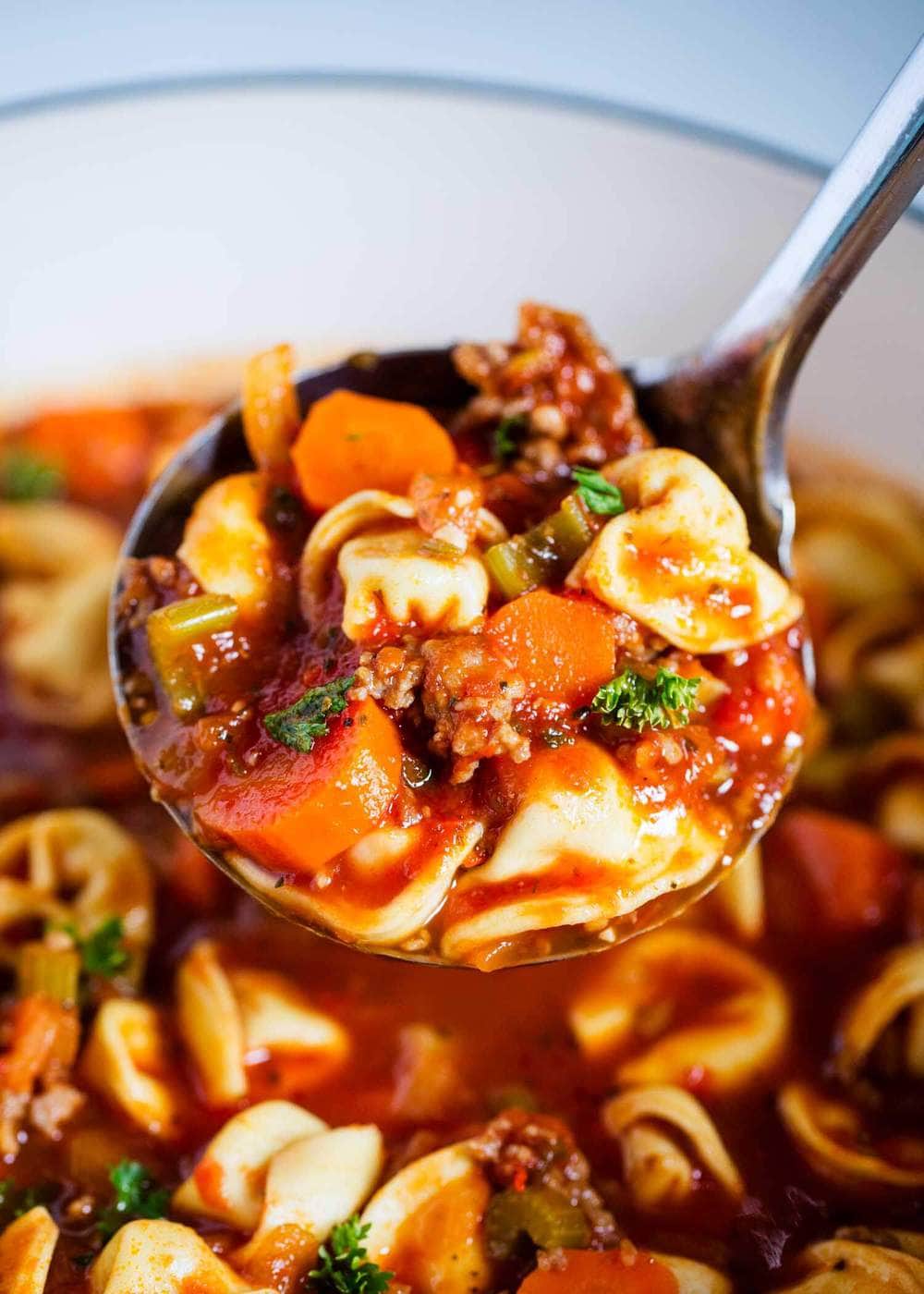 Close up of sausage tortellini soup on a silver ladle 