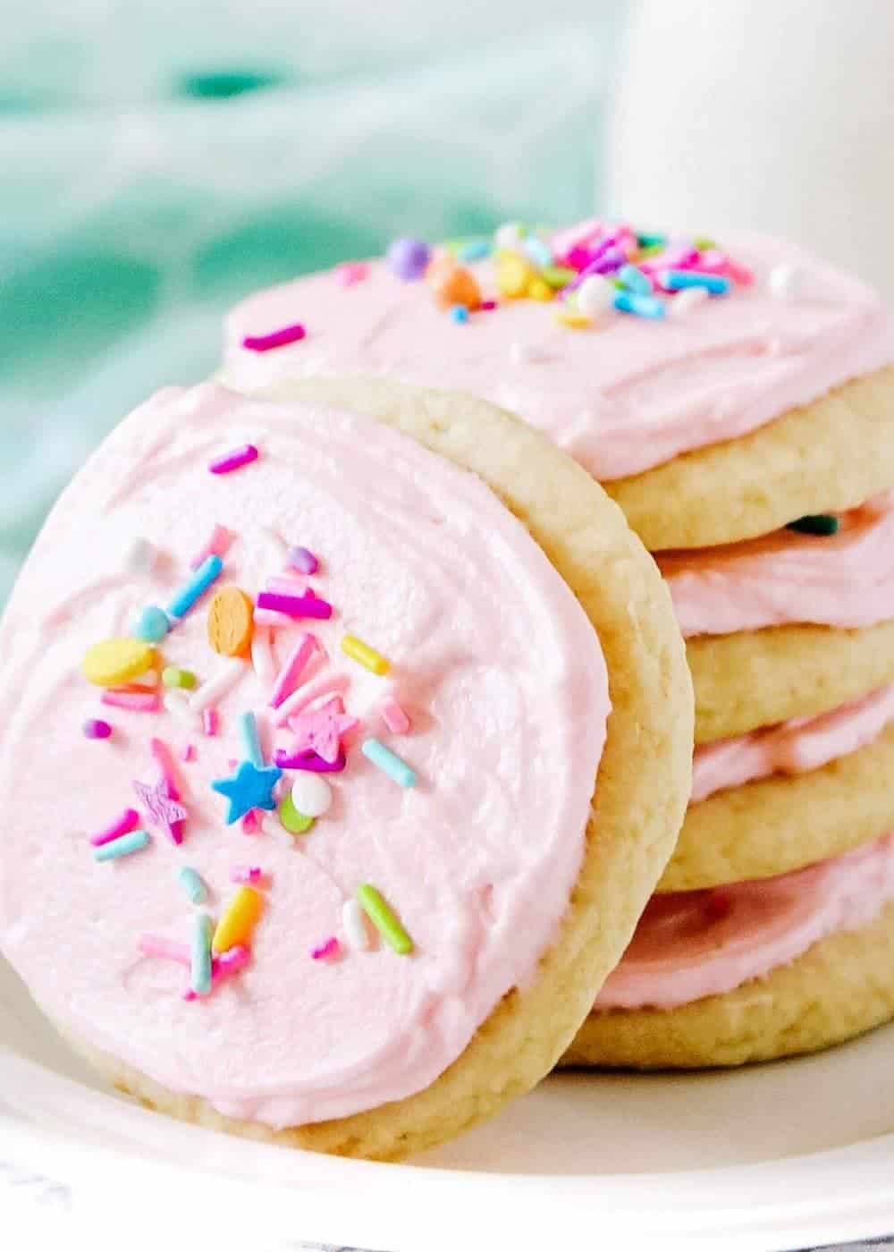 Close up of sugar cookies with pink frosting and sprinkles.