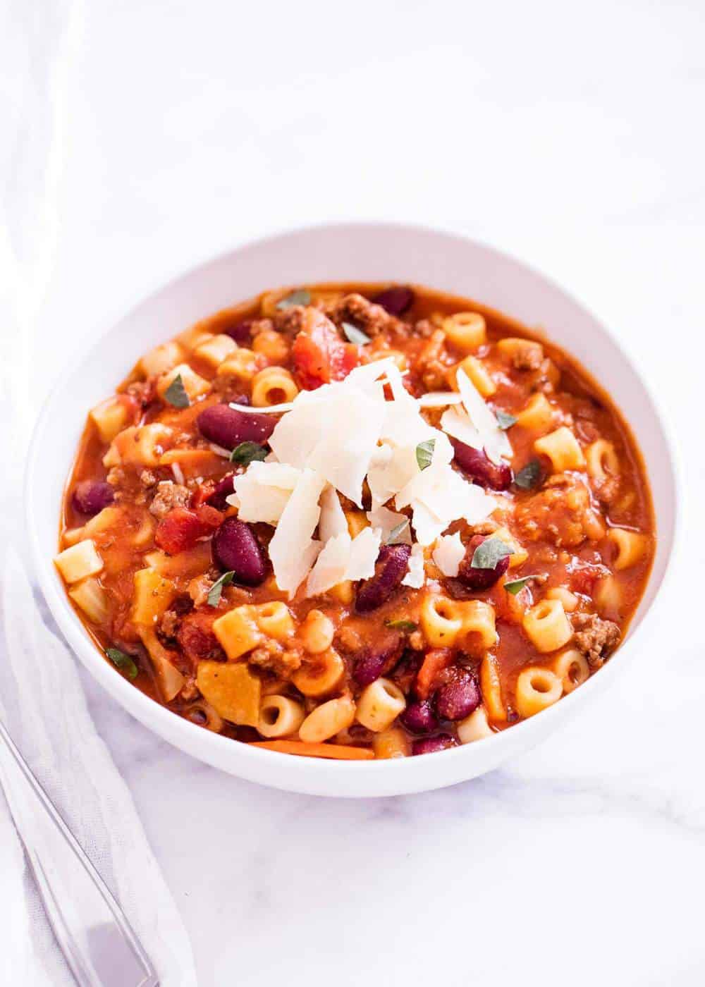 Bowl of pasta fagioli with shaved parmesan on top.