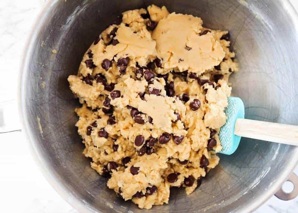 Chocolate chip cookie dough in a metal bowl.