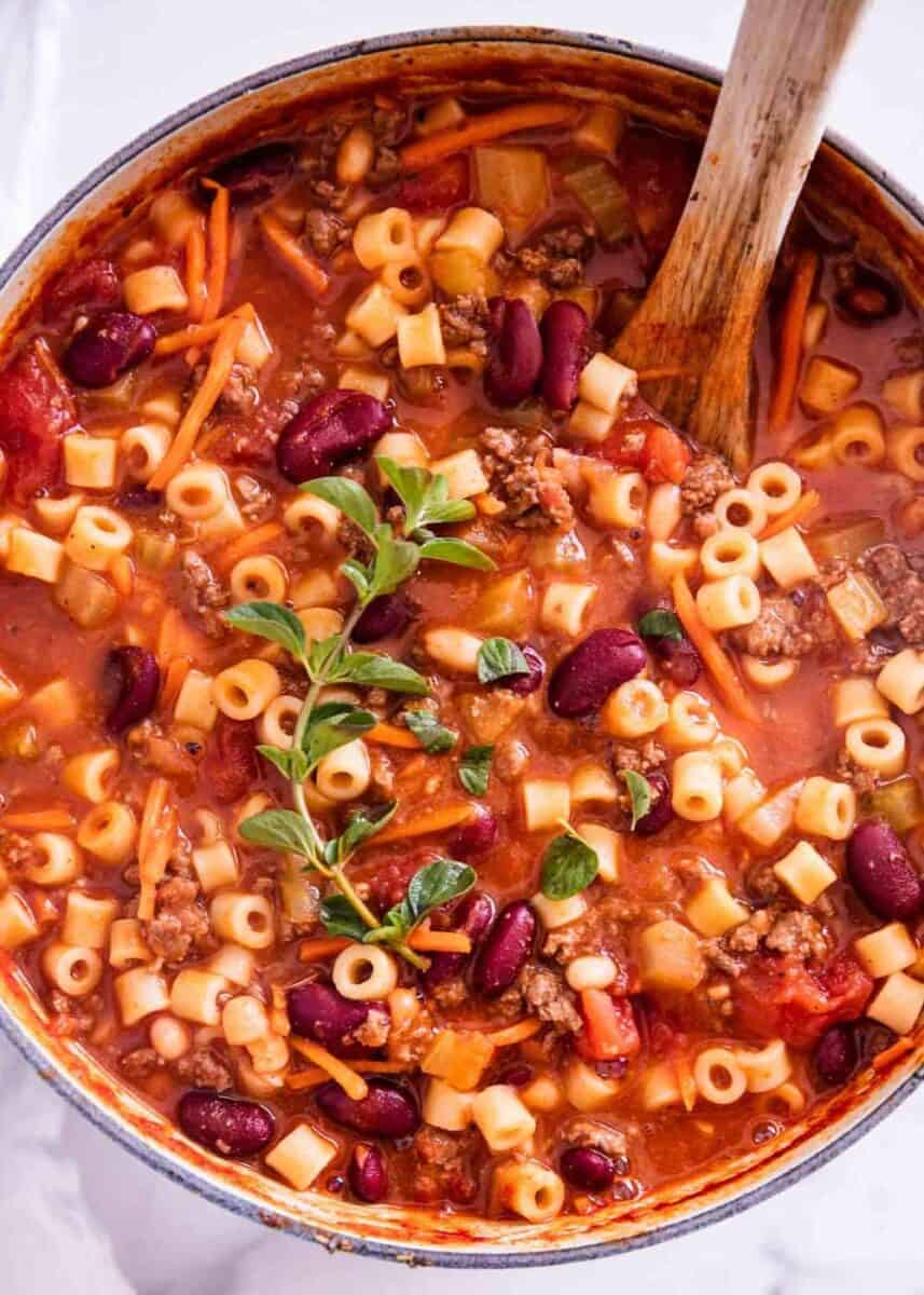 close up of pasta fagioli in pot with wooden spoon 