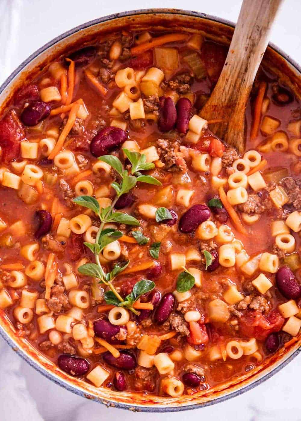 Close up of pasta fagioli in pot with wooden spoon.