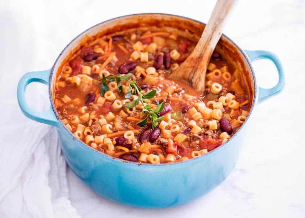 This pasta e fagioli is an easy Olive Garden copycat that's perfect on a cold winter day. It's loaded with fresh veggies, beans, ground beef, seasonings and ditalini pasta. Super hearty and delicious! Pasta fagioli in pot with wooden spoon.