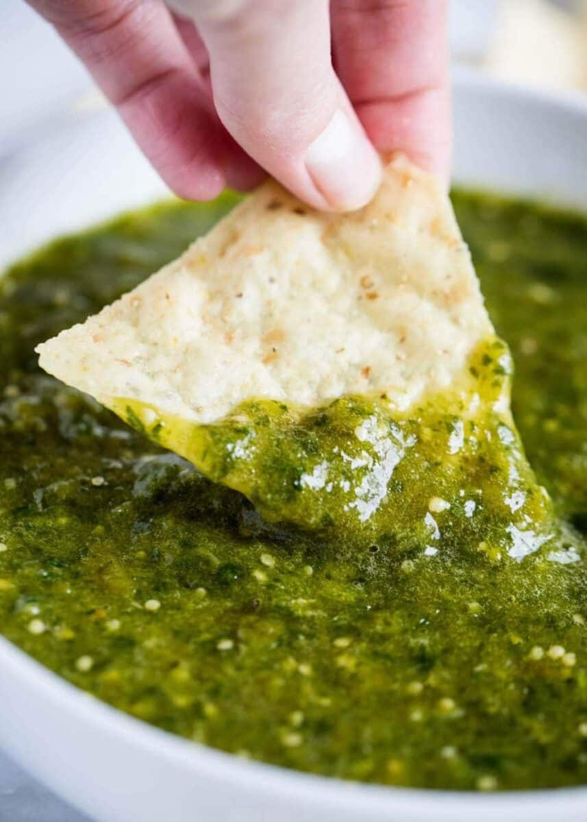dipping tortilla chip in salsa verde 