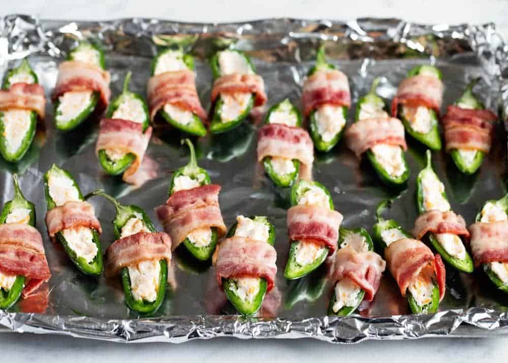 Bacon wrapped jalapeno poppers on a baking sheet.