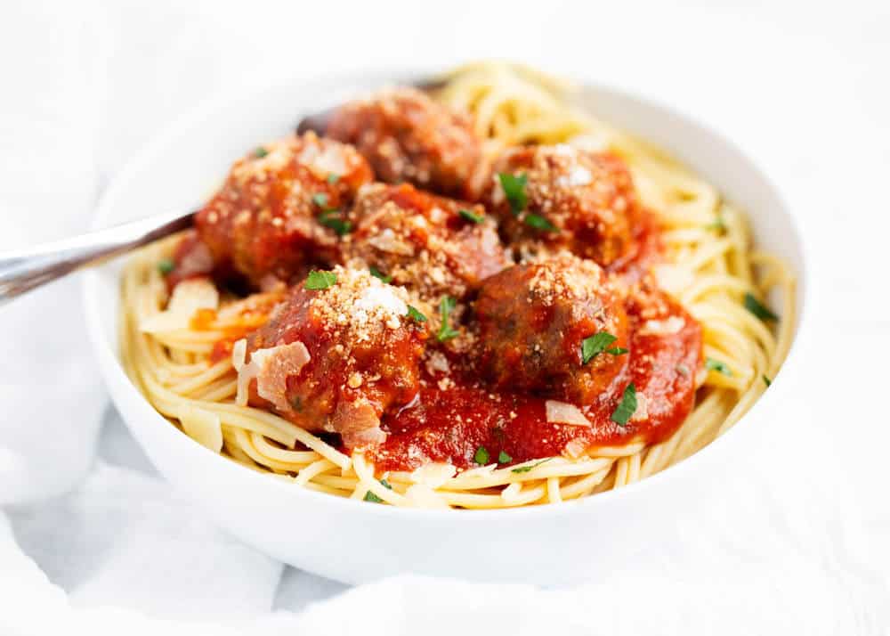 spaghetti and meatballs in a white bowl