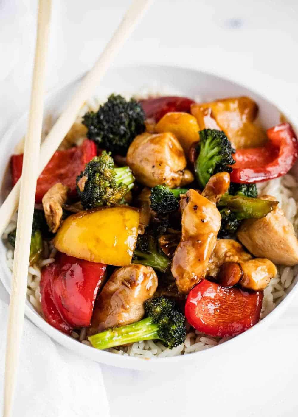 Chicken and vegetable stir fry in bowl with chopsticks.