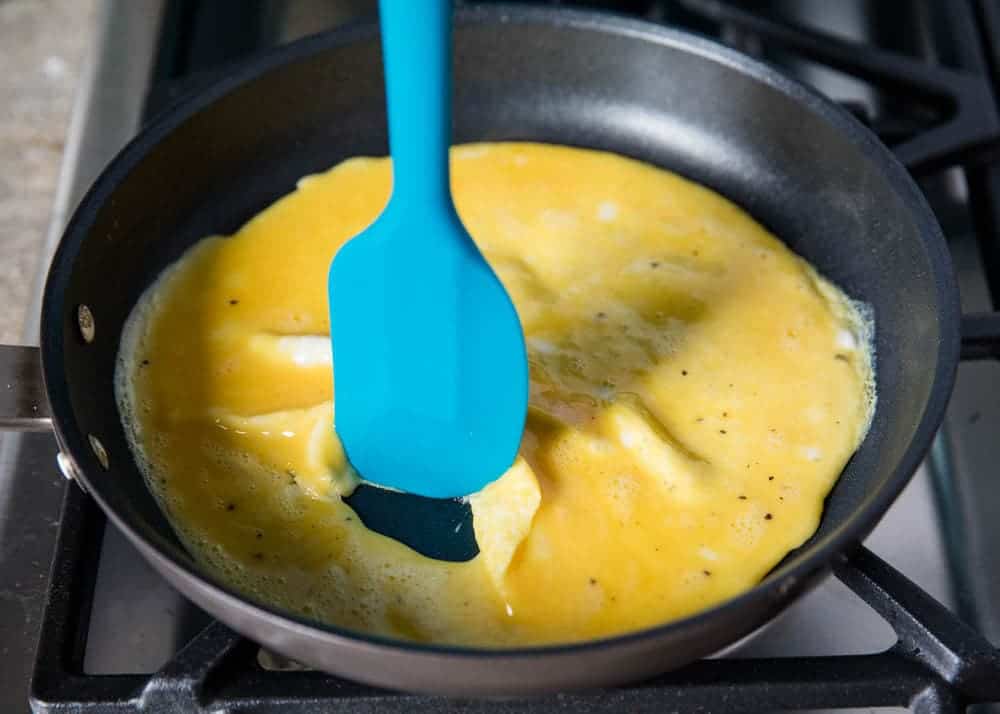 Pushing eggs in skillet with a spatula.