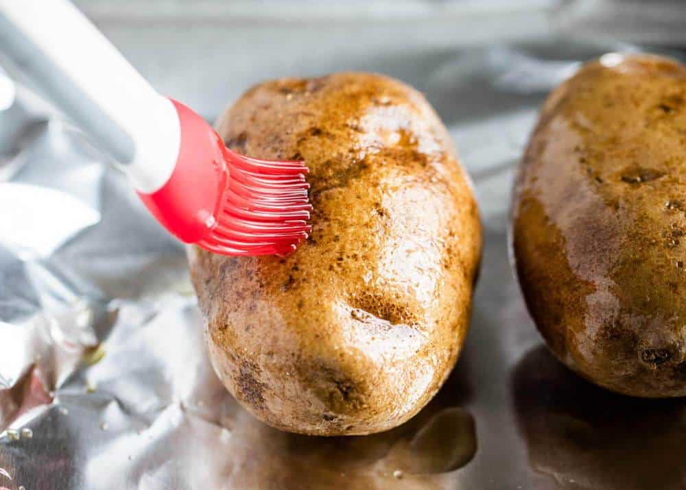 brushing oil on a russet potato 