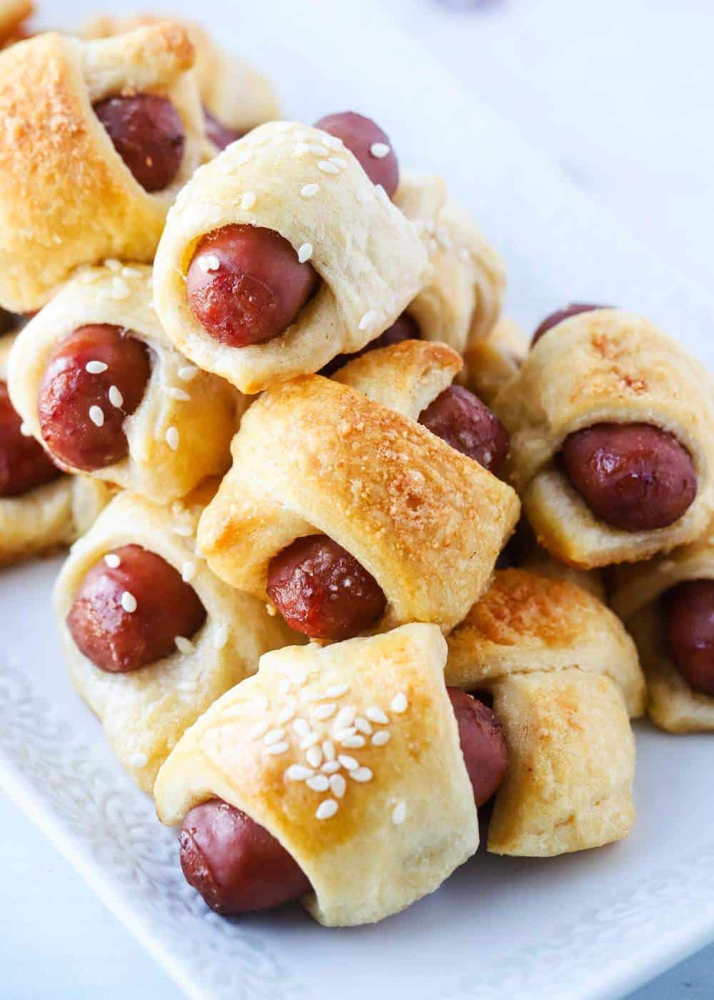Pigs in a blanket stacked on plate.