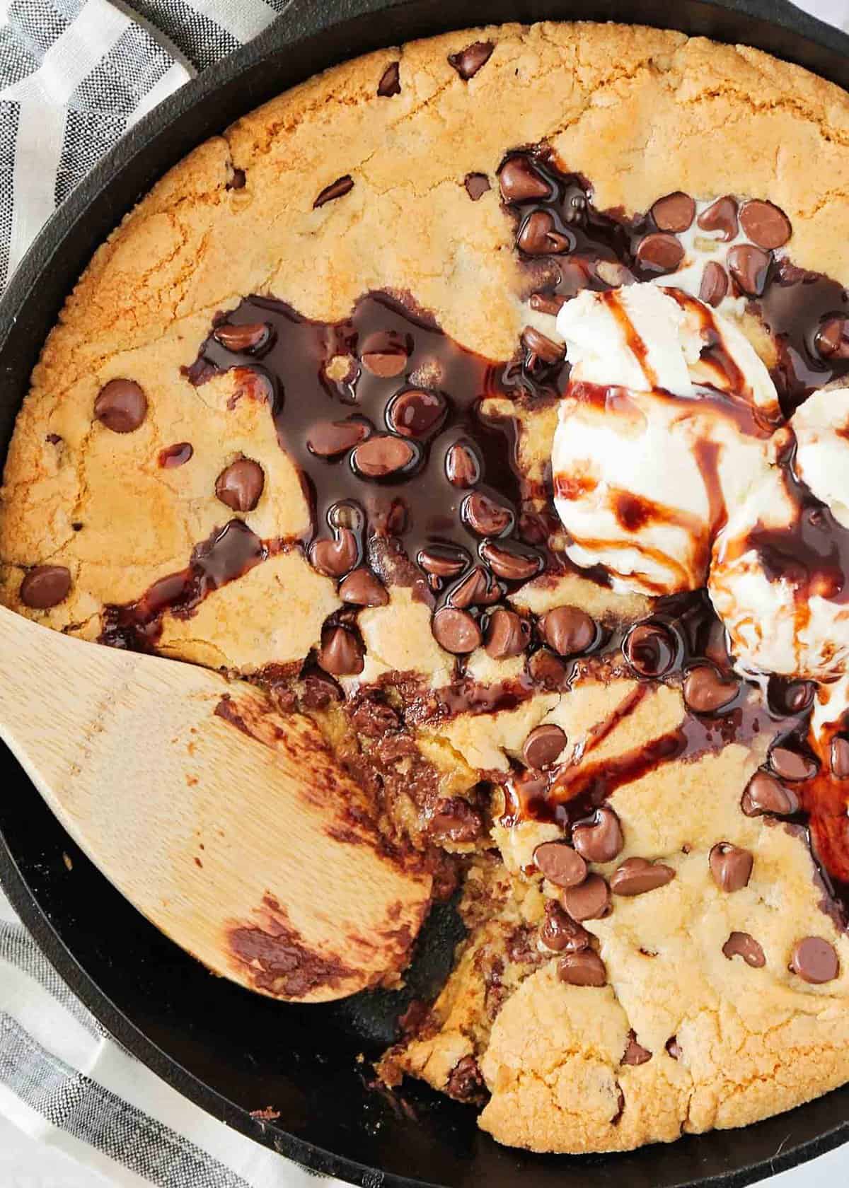 Chocolate chip cookie in a cast iron skillet with spoon.
