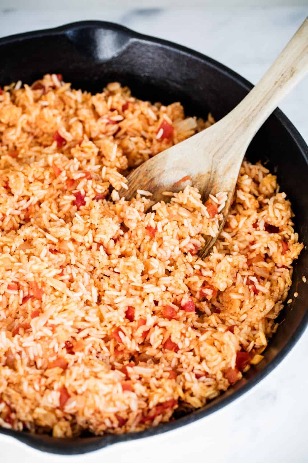 Mexican rice in a cast iron skillet with a wooden spoon 
