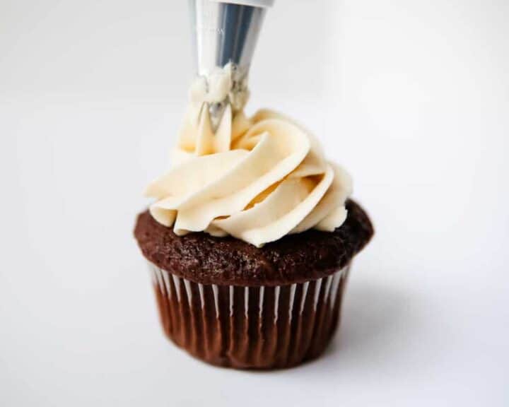 piping classic buttercream on a chocolate cupcake 