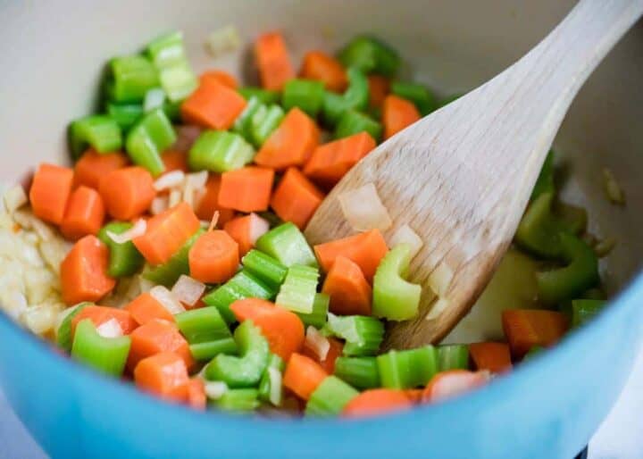 cooking diced veggies in pot with wooden spoon 