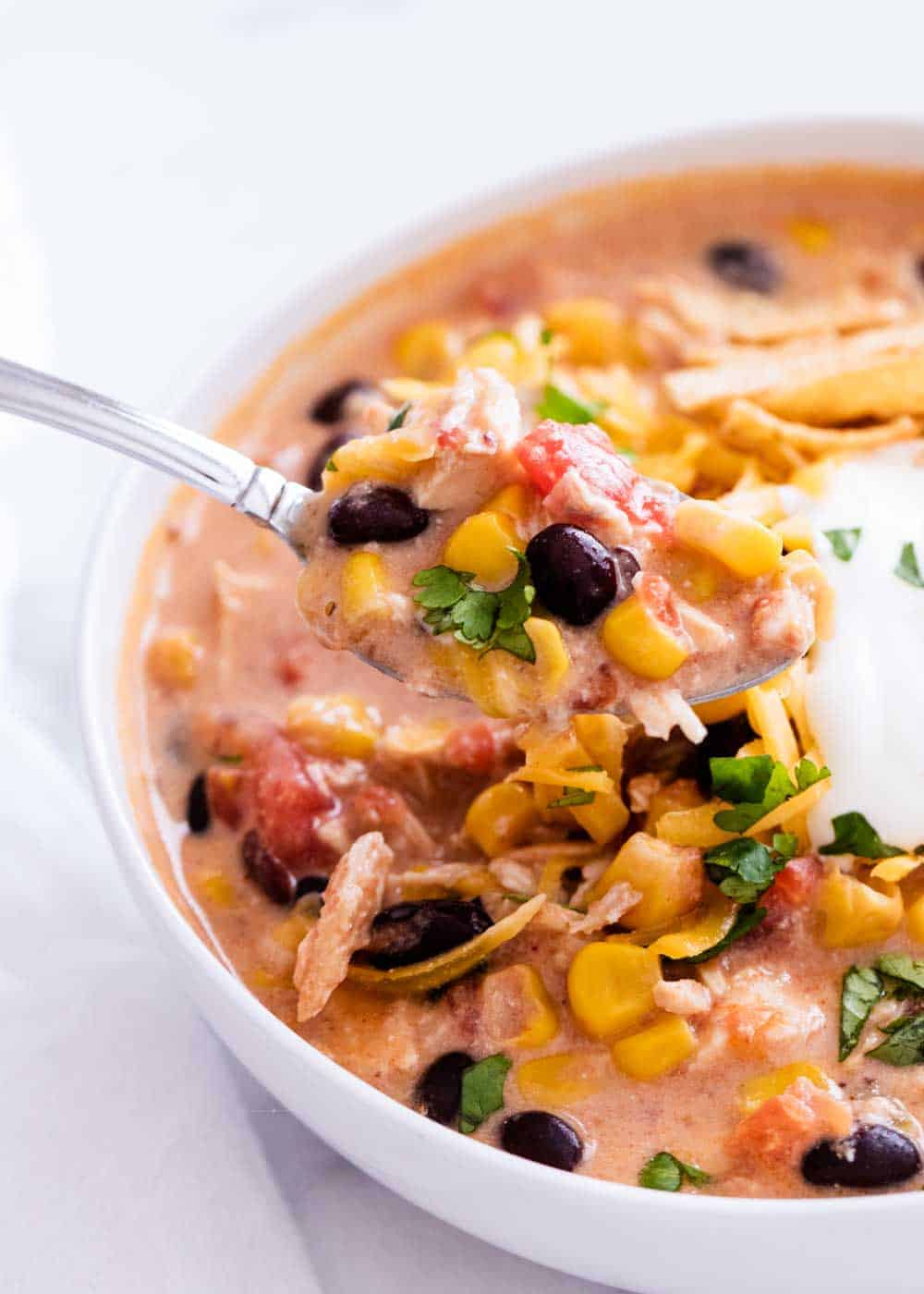 Bowl of chicken enchilada soup with a spoon.