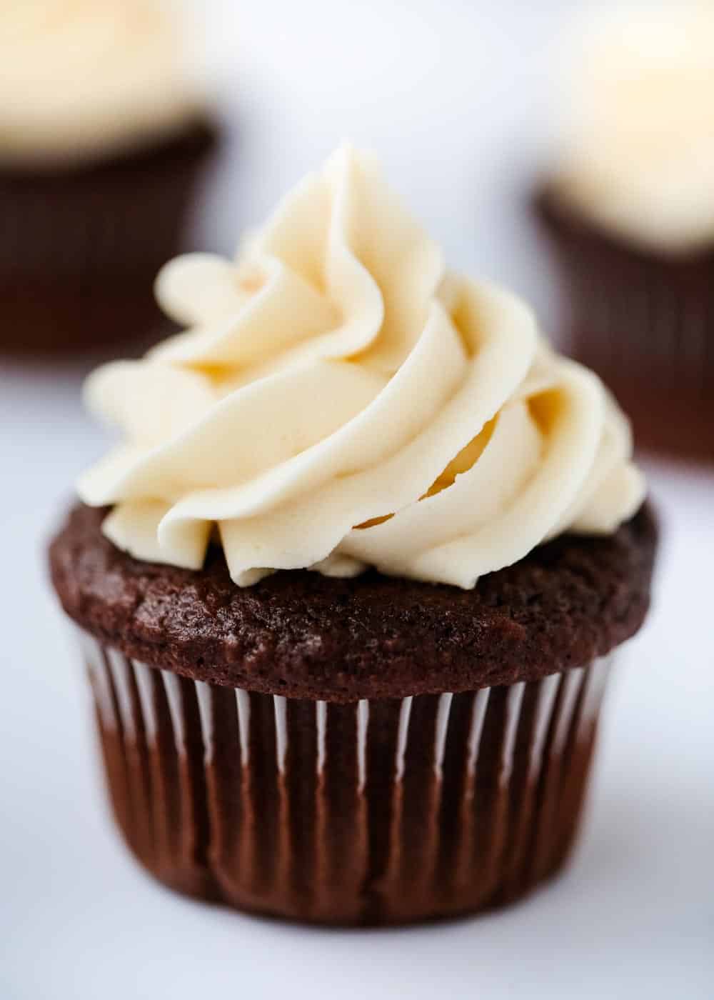 This is simply the BEST chocolate cupcake recipe that you can make from a cake mix. They are super soft, rich and topped with a lush buttercream frosting. You won't believe how easy these are to make! Close up of a chocolate cupcake with buttercream frosting.