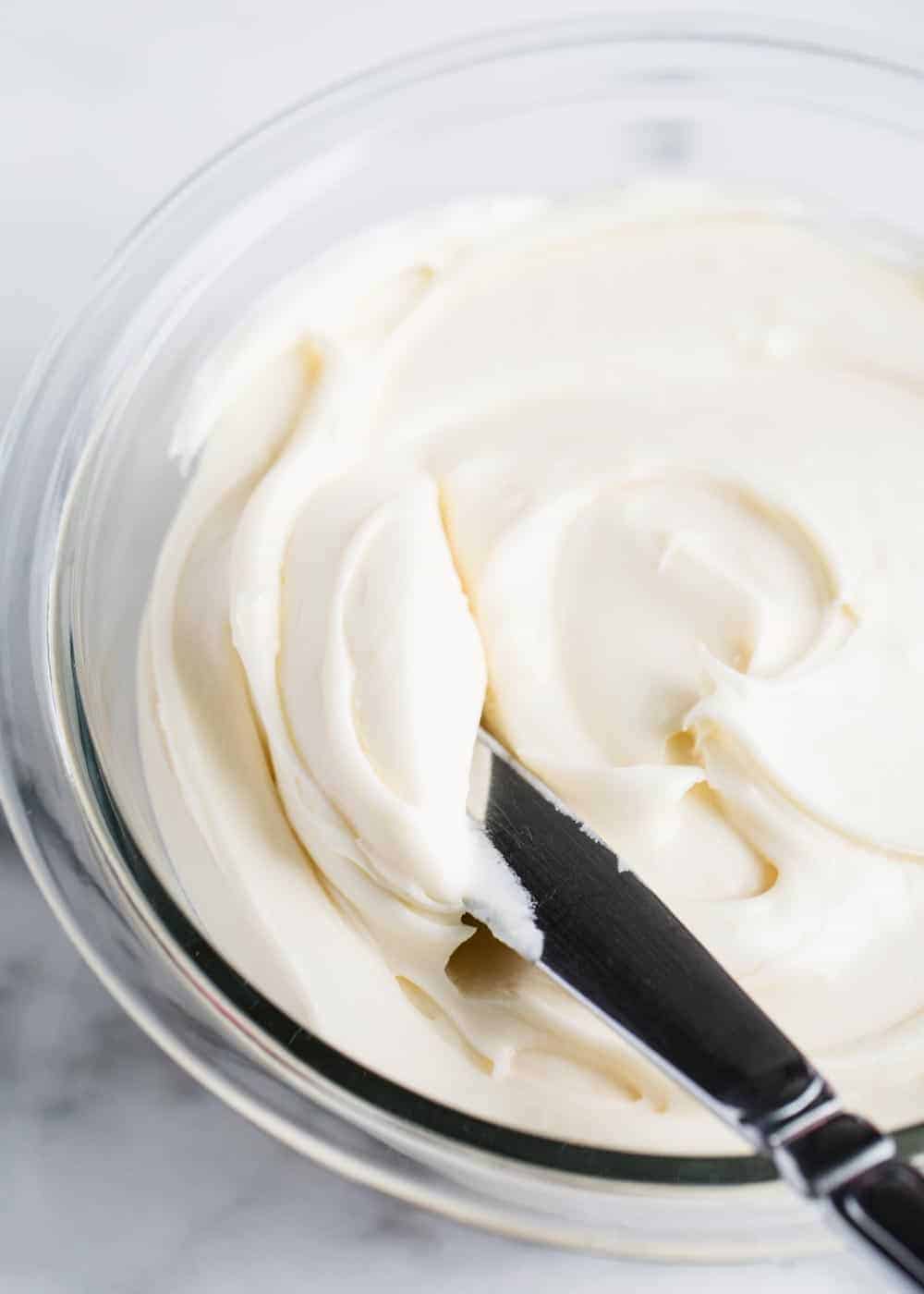 Spreading cream cheese frosting with knife.