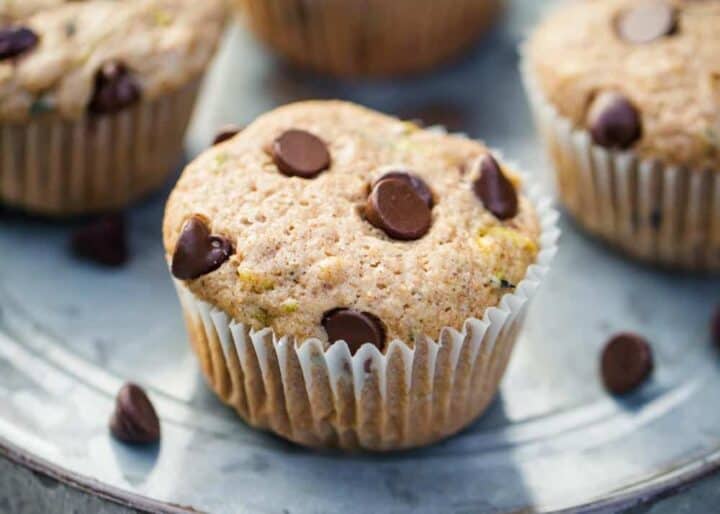 These zucchini chocolate chip muffins are super soft, moist and jam packed with flavor! You'd never know they're loaded with freshly shredded zucchini. Kid approved and freezer-friendly, too! chocolate chip zucchini muffins on metal plate