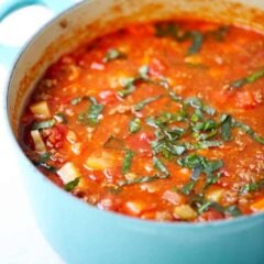 Hearty vegetable soup in a blue pot.