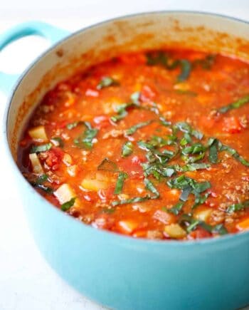 Hearty vegetable soup in a blue pot.