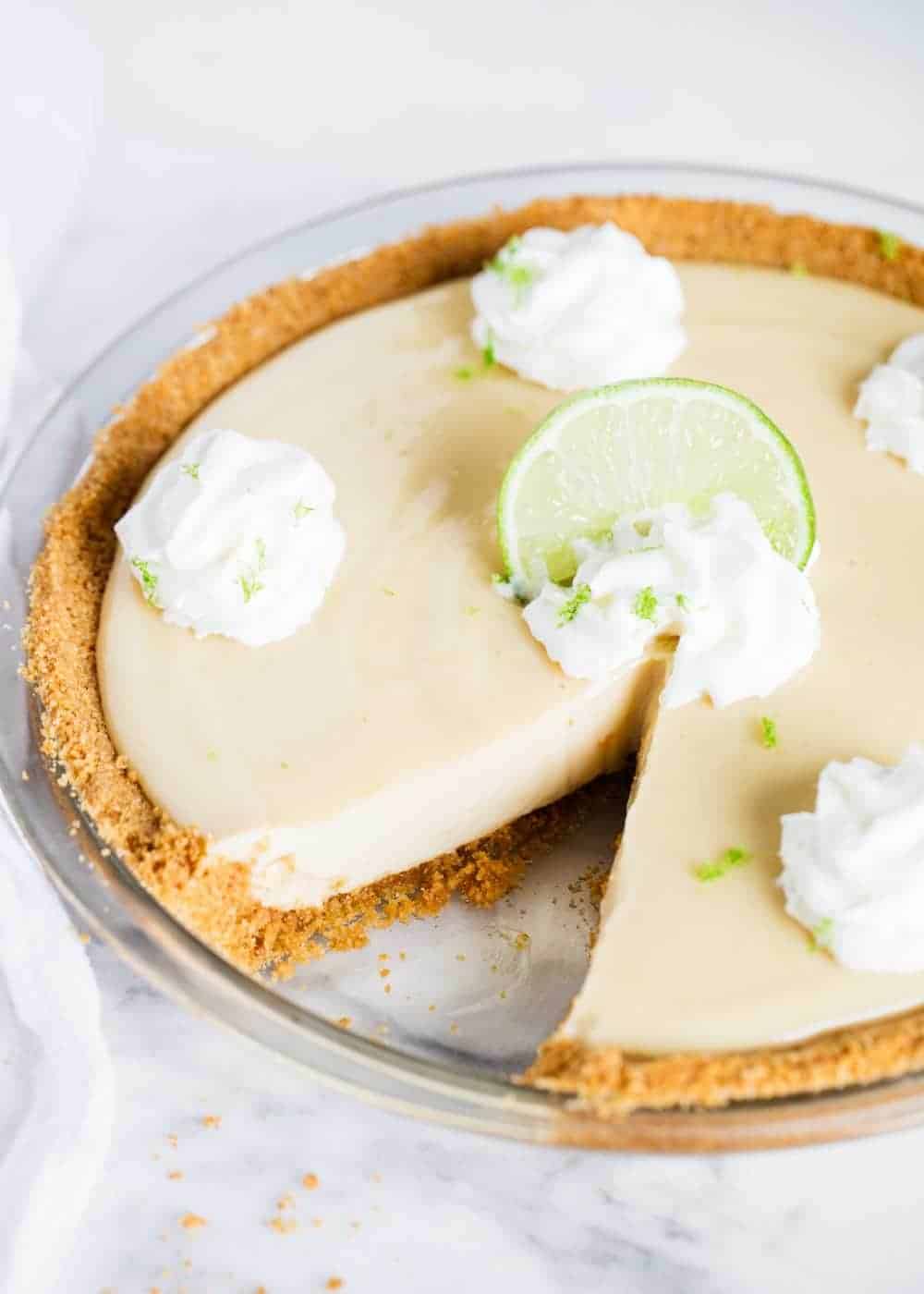 This easy key lime pie is made with just 5 ingredients and is so simple to whip up! It packs a punch of sweet flavor and is super tart and creamy. Perfect to enjoy all year long! Key lime pie with a slice taken out.