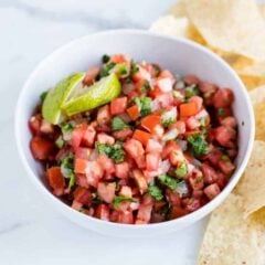 A bowl of quick and easy pico de gallo with tortilla chips to the side for scooping the fresh dip.