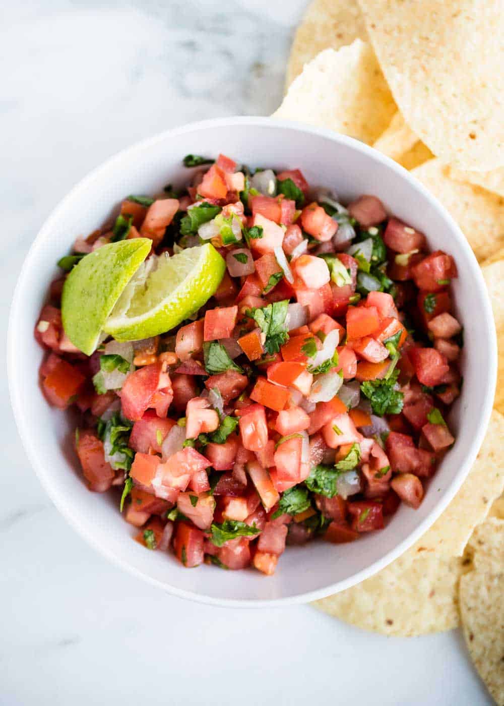 Bowl of pico de gallo with lime wedges.