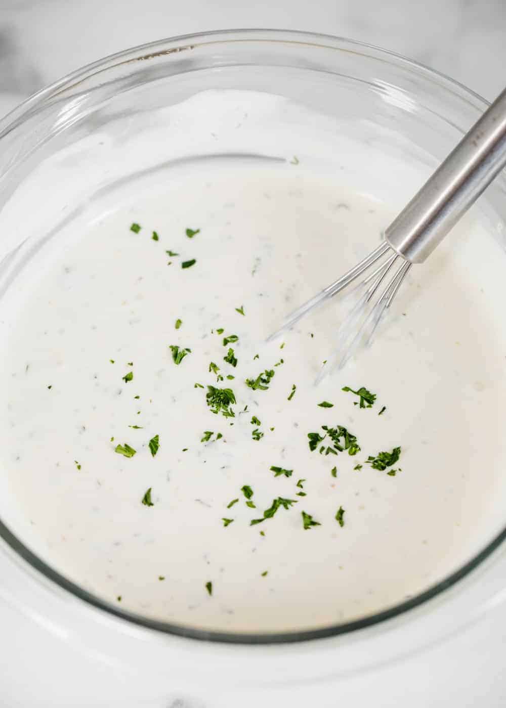 Whisking ranch dressing in bowl.