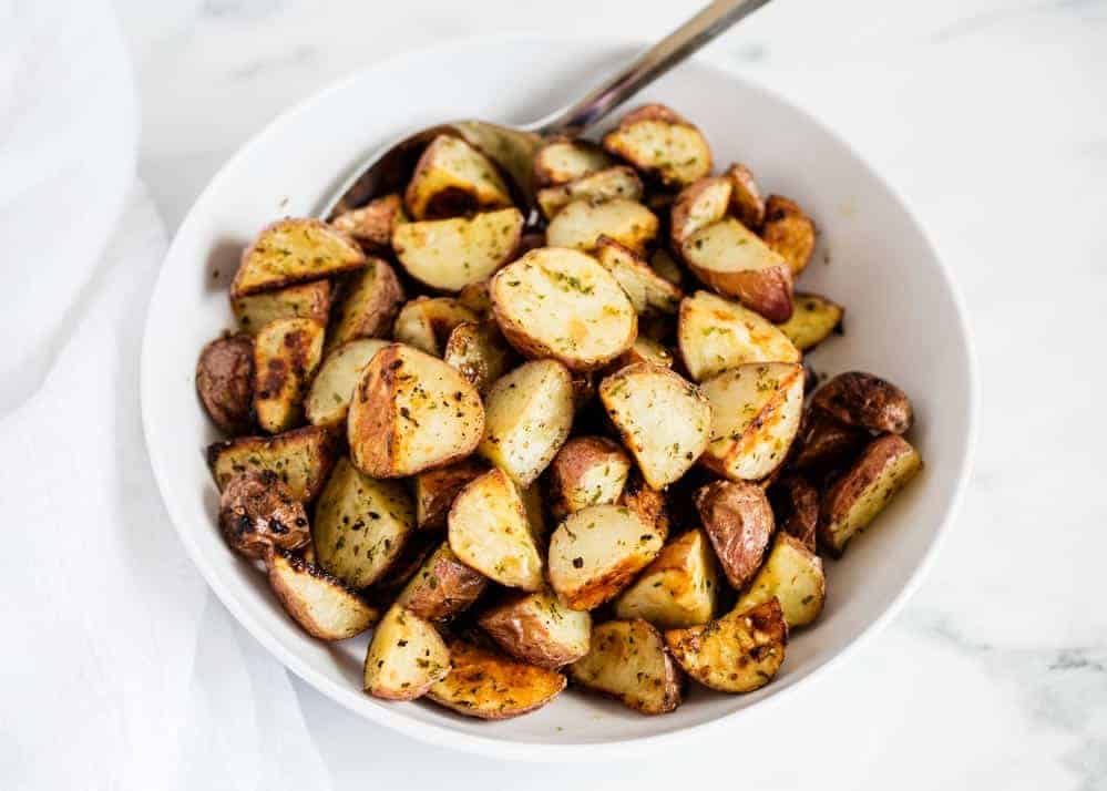 Baked red potatoes in white bowl.