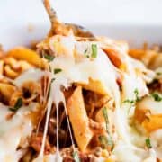 A close up of cheesy baked ziti on a fork