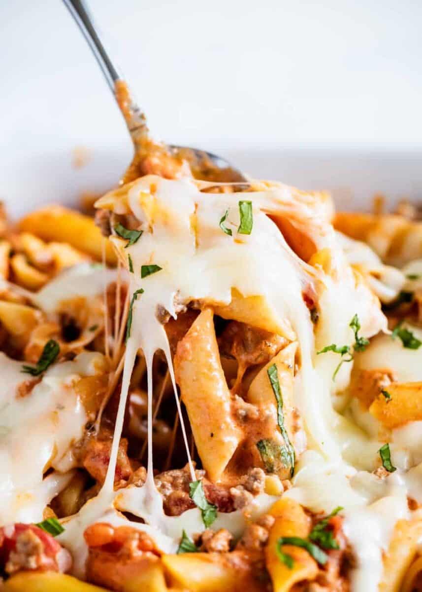 A close up of cheesy baked ziti on a fork 